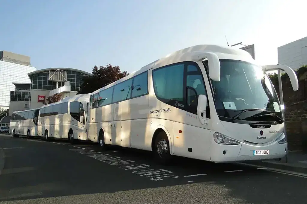 A modern, fully audited Tranzcare midi coach parked at a Manchester educational venue for a safe school day trip. Exterior profile of a Euro 6 compliant Tranzcare large coach utilised for high-capacity school charter and university excursions.