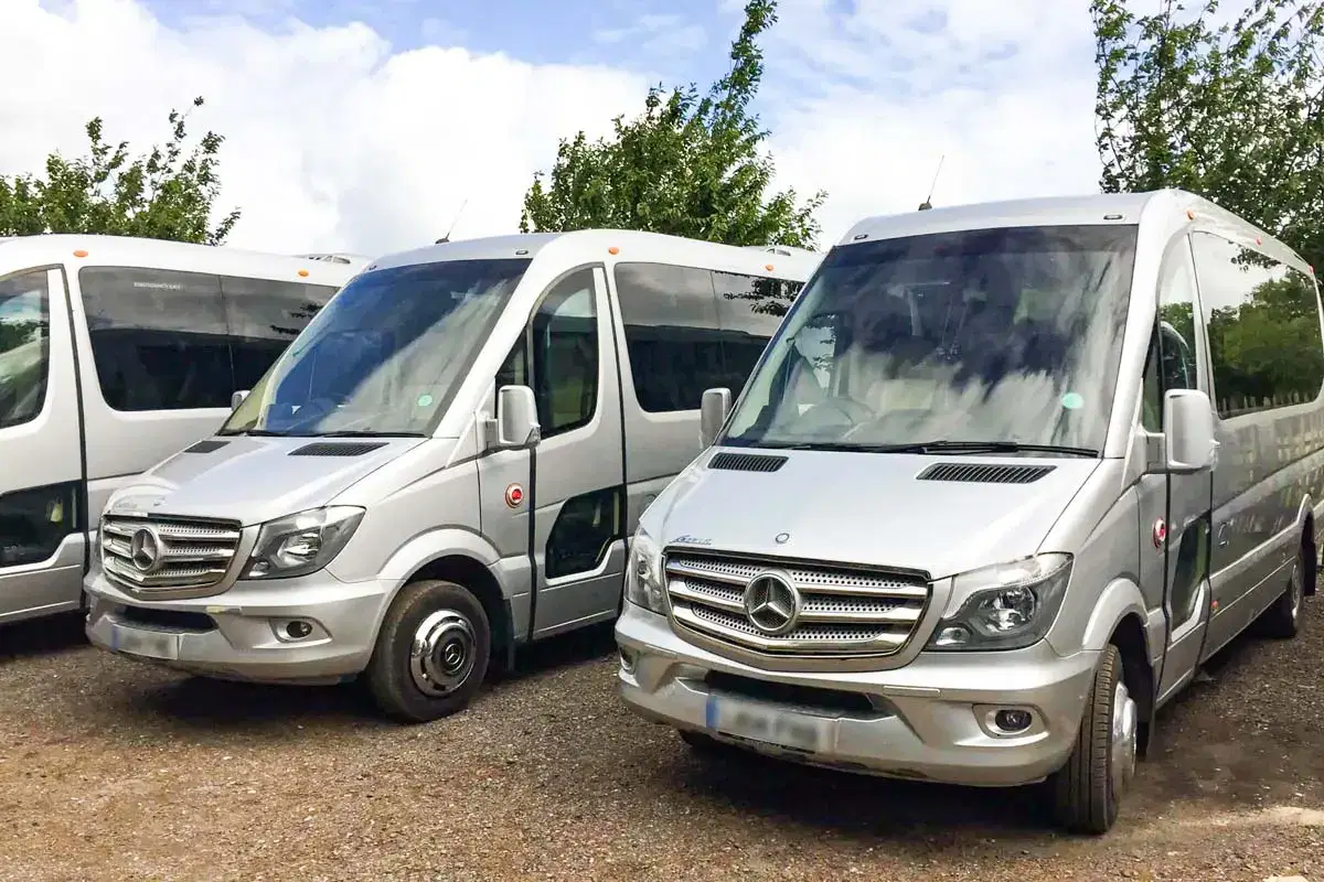 Front view of a sleek Tranzcare luxury 30-seater midi coach demonstrating premium corporate transport presentation.