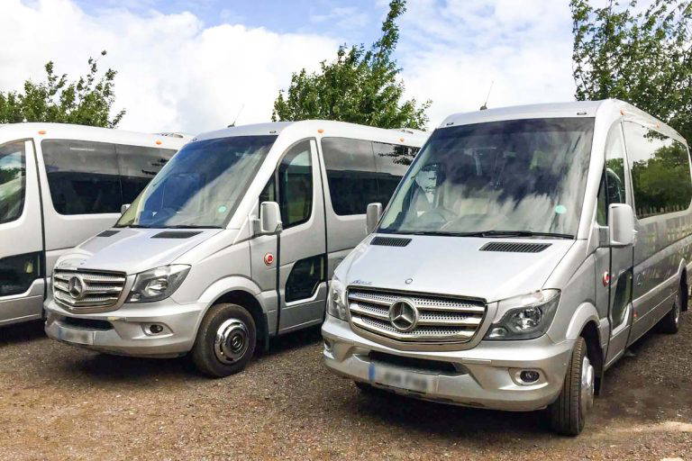 Front view of a sleek Tranzcare luxury 30-seater midi coach demonstrating premium corporate transport presentation.