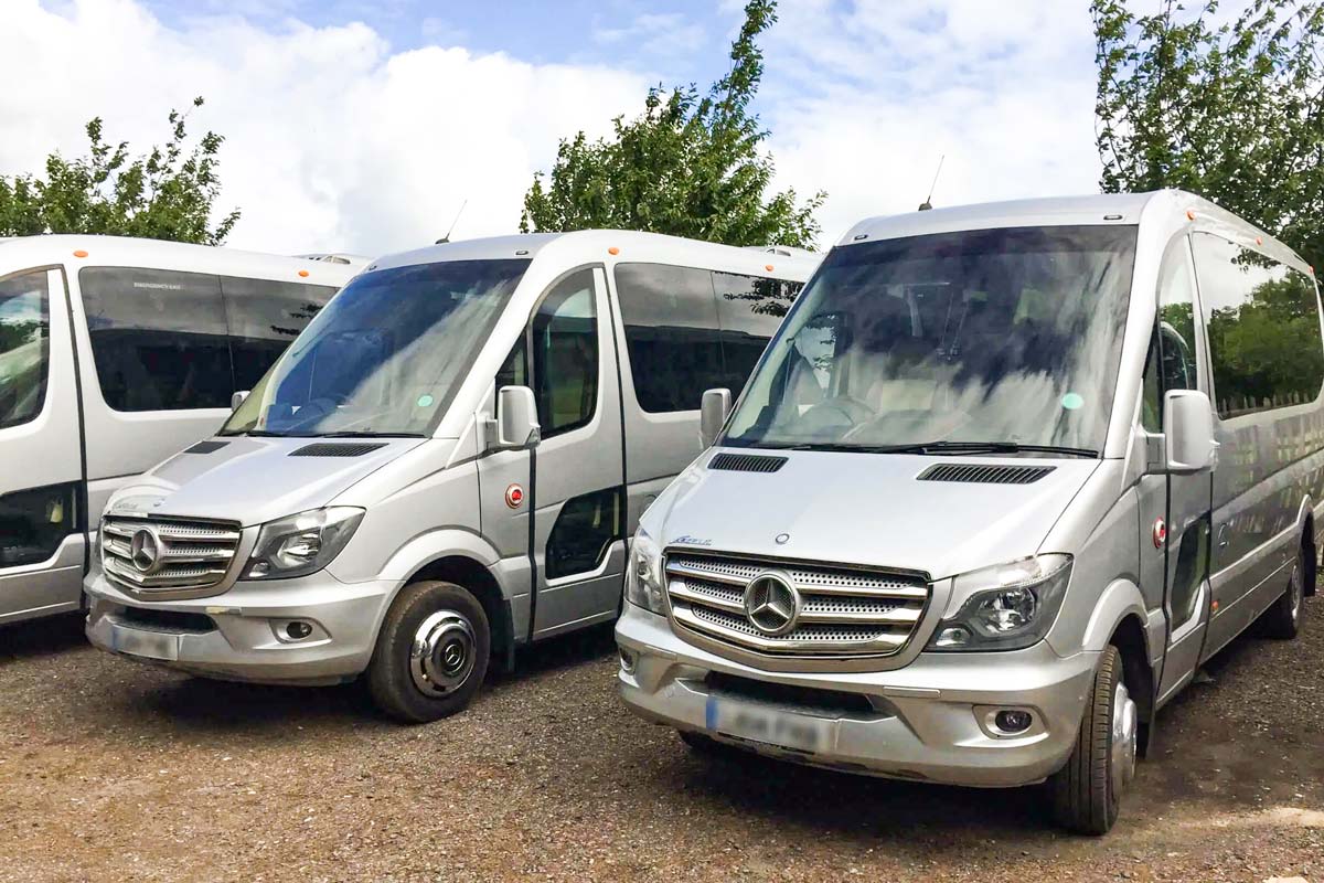 Front view of a sleek Tranzcare luxury 30-seater midi coach demonstrating premium corporate transport presentation.